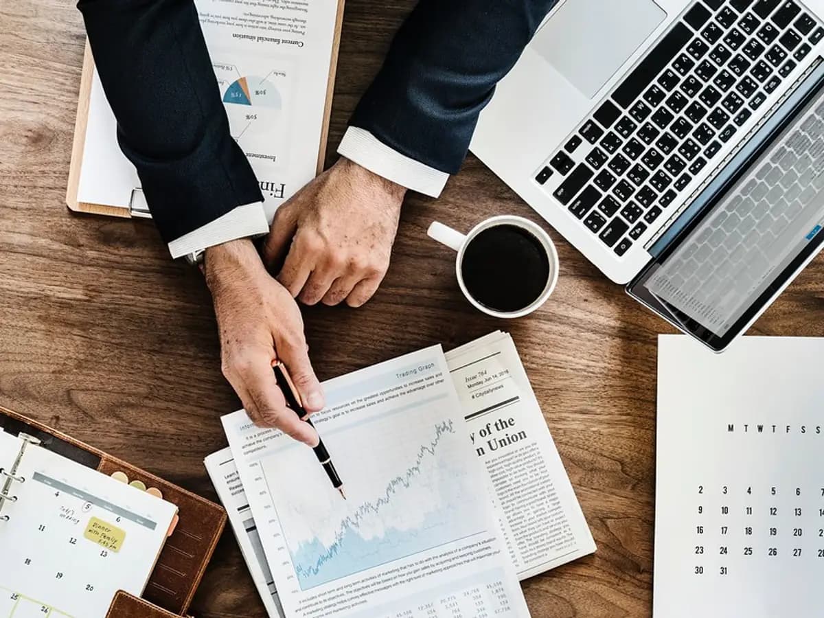Hands marking up printed charts beside a laptop