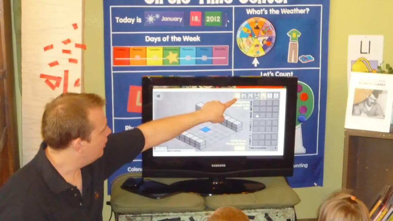 A teacher working at a desk in a classroom
