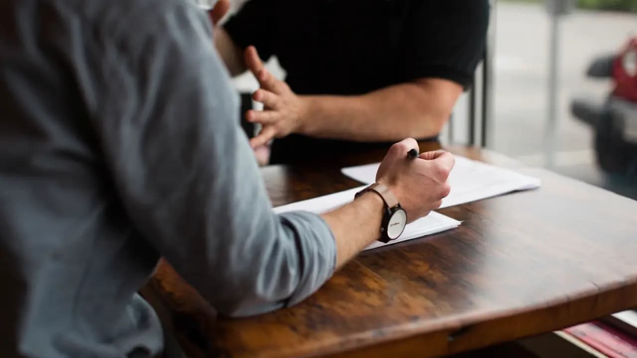 Two colleagues reviewing written notes across a desk