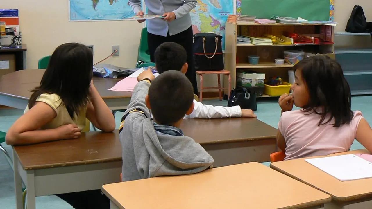 A teacher standing over pupils working at their desks