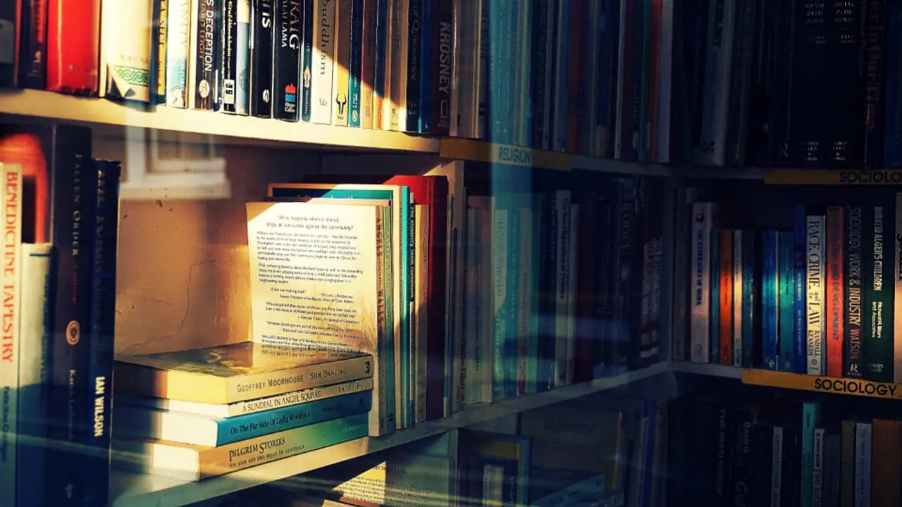An open book resting on a full library shelf