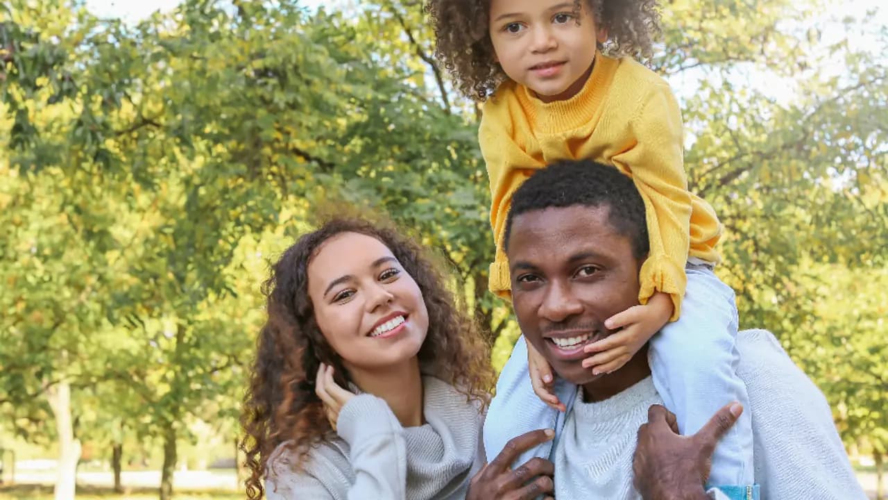 A parent carrying a small child on their shoulders
