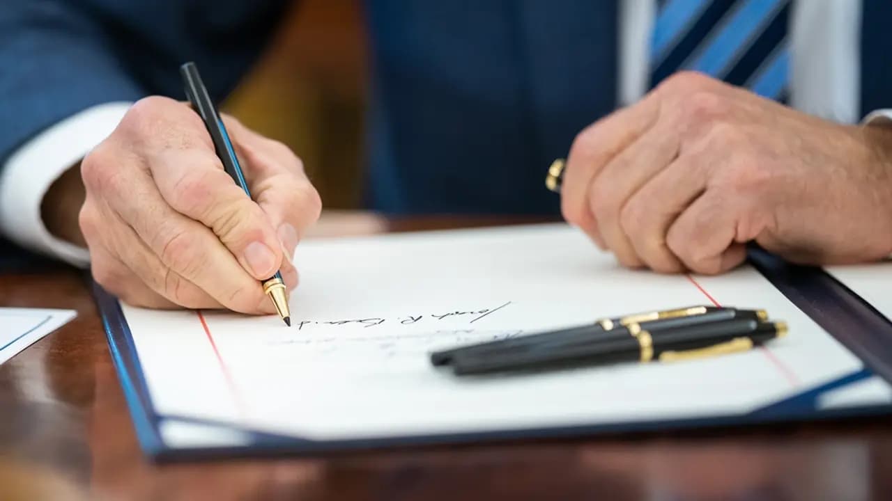 A hand signing a document held open in a folder