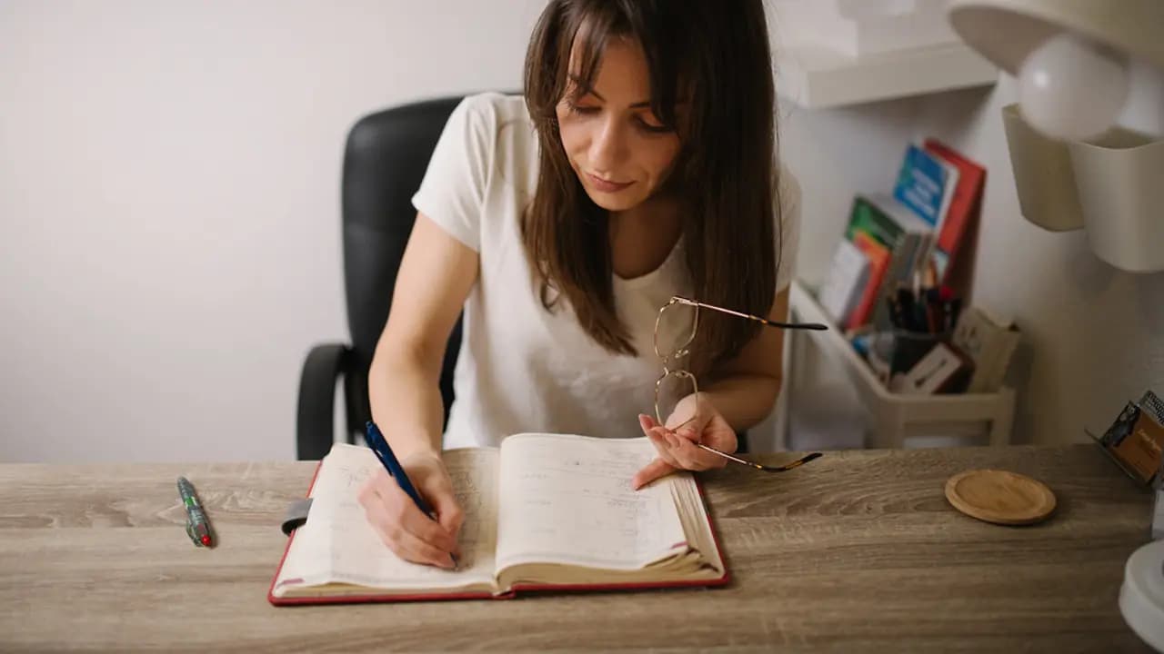 A teacher writing in a notebook at a desk