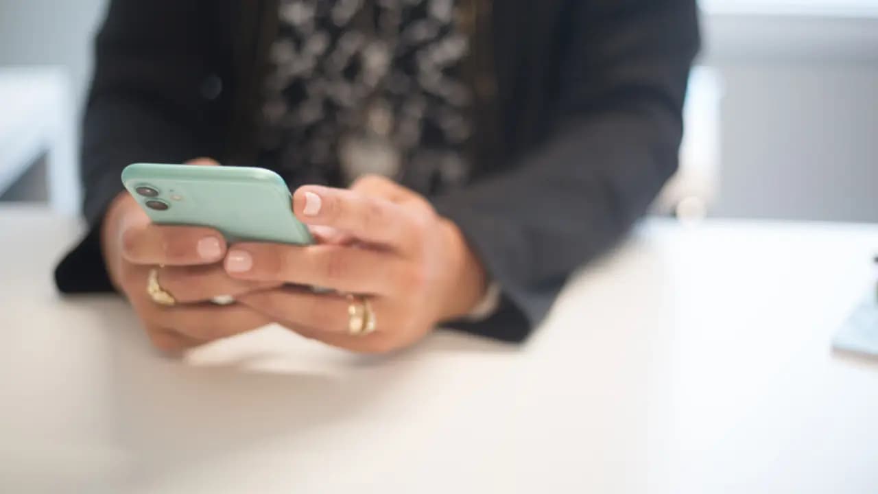 Hands holding a phone at a desk