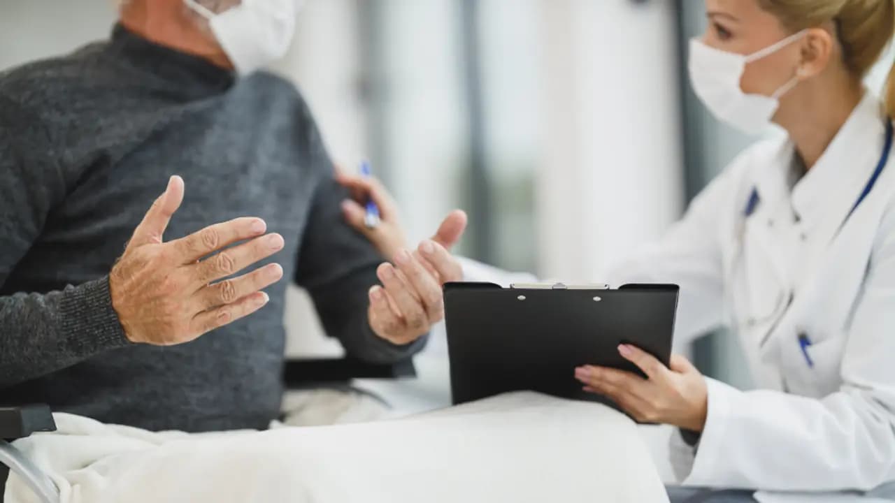 A clinician with a clipboard talking to a patient
